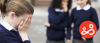 An upset school girl is a victim of bullying, as her peers taunt her in the background