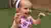 A child wearing a union jack dress and smiling at a buttons nursery coronation picnic.