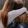 Two young women have their arms wrapped around each other and are sharing experiences, to help ease stress and anxiety