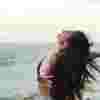 Woman on a beach smiling and extending her arms