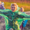 A group of kids running together wearing colourful rain macs