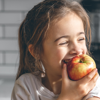 A child eating an apple, and making a healthy eating choice