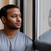 Young man staring at reflection in the window, learning to be the father he never had.