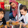 A mother is looking after her children, whilst they play outdoors