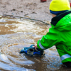 A young boy playing with a toy truck in a puddle