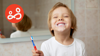 a boy smiles at the camera while cleaning his teeth