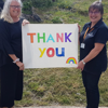 Two team members of HMP Winchester holding a 'thank you' sign, in response to the recognition they received for their work during the pandemic