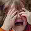 Toddler girl covering her eyes and screaming