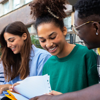 A group of young carers sharing study notes outside of a school building