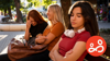 Two teenage girls are laughing together, whilst another girl is not part of the fun and looks troubled