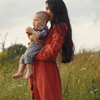 A mother holds her child while stood in a field.