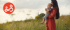 A mother holds her child while stood in a field.