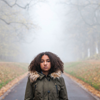 A young woman standing in a path between trees, struggling with climate anxiety