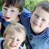 Three young brothers, set aside their sibling rivalry, to pose for a photo in which they appear well-behaved.