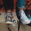 Two teenage friends sat together at the top of a skate park ramp