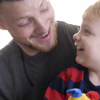 A father shares a happy moment with his son, who is playing with a toy