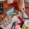 Two children are enjoying an art activity during the summer, on a table covered with art materials.