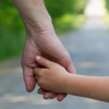 A parent and child holding hands whilst walking down a country lane