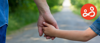 A parent and child holding hands whilst walking down a country lane